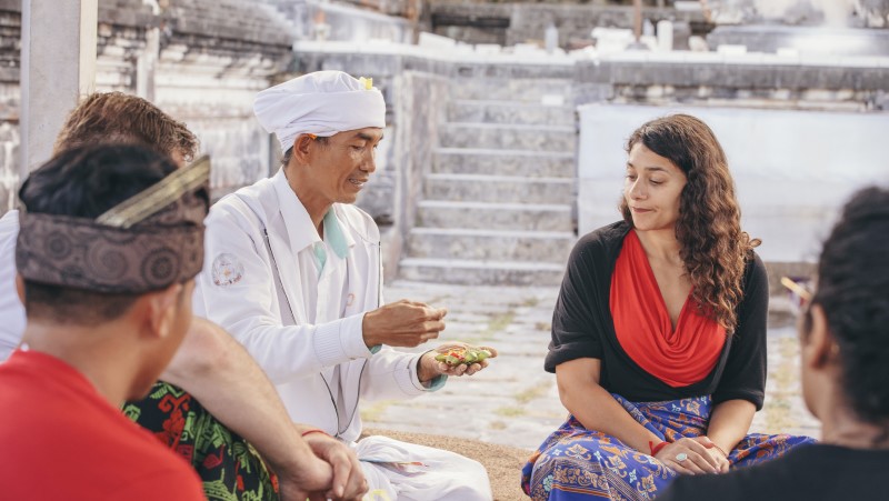 Priest blessing solo female traveller in Bali
