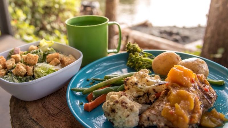 A plate of delicious food and a cup of tea at a campsite