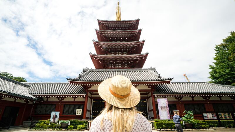 A woman wearing a large hat looking at a temple in Japan